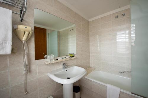 y baño con lavabo, bañera y espejo. en Hotel Borrell, en Olot