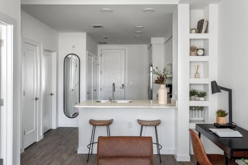 a kitchen with a sink and a counter with stools at Locale The Gulch - Nashville in Nashville