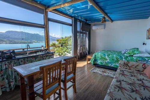 a room with a table and chairs and a large window at Cobertura com Incrível Vista de Cinema para o Mar in Ilhabela