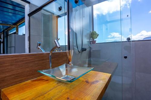 y baño con lavabo de cristal sobre una mesa de madera. en Cobertura com Incrível Vista de Cinema para o Mar, en Ilhabela
