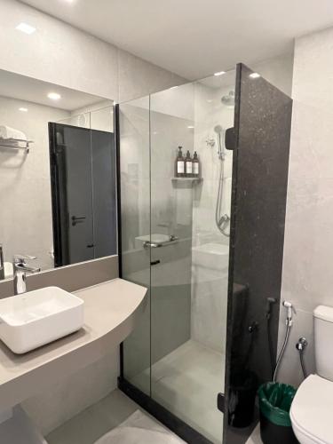 uma casa de banho com um chuveiro e um lavatório. em Apart suite frente ao mar no Rio de Janeiro