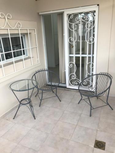 - deux chaises et une table en verre sur une terrasse couverte dans l'établissement Junín Dptos 2, à San Fernando del Valle de Catamarca