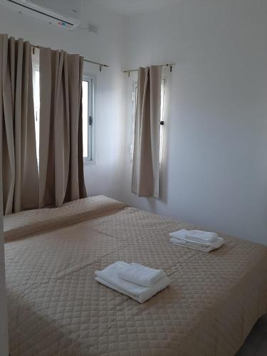 a white bedroom with two beds with towels on them at Junín Dptos 2 in San Fernando del Valle de Catamarca