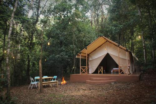 a tent in the middle of a forest with a fire at ELA Glamping Madikeri in Madikeri