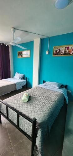 伊卡的住宿－La Casa de Bamboo，一间卧室设有两张床和蓝色的墙壁