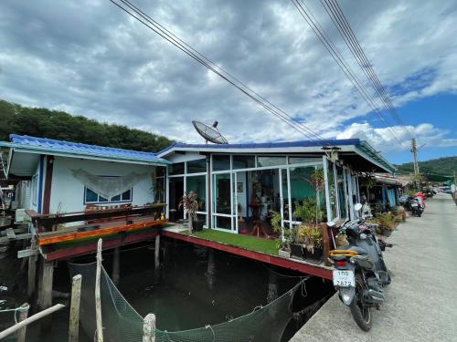 a house on the water with a motorcycle parked next to it at Dutchman Homestay in Ko Kood