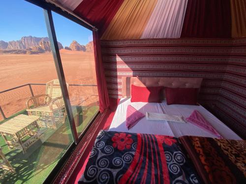 a bed in a room with a view of the desert at Desert shine camp in Wadi Rum
