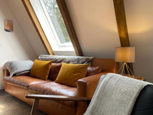 a brown leather couch in a room with a window at Wald-Chalet Vulkaneifel in Kerschenbach