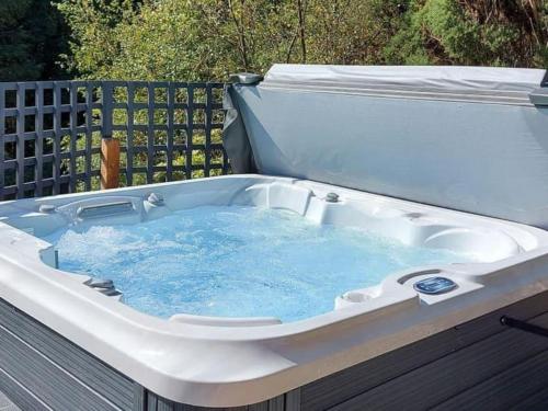 a hot tub with blue water in it at Treetops Luxury Log Cabin - Hot tub, BBQ & Sauna in Kippford