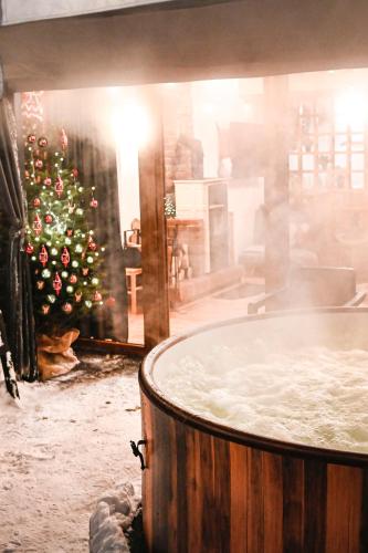 a christmas tree in a room with a bath tub at STRÓŻÓWKA SKI&SPA Domek nad rzeką z ogrodem i jacuzzi,narty. in Stróża
