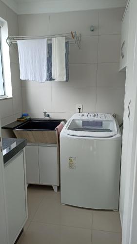 a small kitchen with a sink and a washing machine at Apto temporada Itapema sc in Itapema