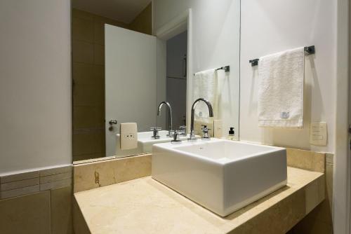 a bathroom with a large white sink and a mirror at 2 Quartos/ 2 banheiros Entre Copa Ipanema Arpoador in Rio de Janeiro