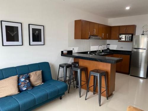 uma sala de estar com um sofá azul e uma cozinha em Departamento nuevo con excelente ubicación! em Mazatlán