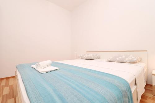 a white bed with a blue blanket and towels on it at Apartments Prižba Bay in Prizba