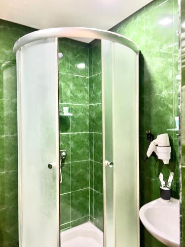 a green bathroom with a shower and a sink at GABATA INN in Bakuriani