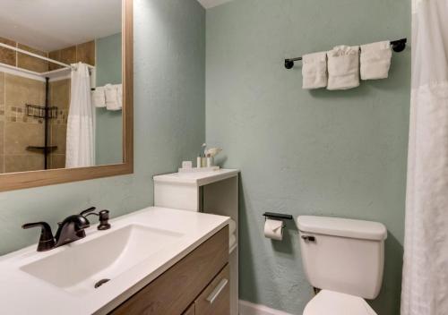 a bathroom with a sink and a toilet and a mirror at Palm Suites in Atlantic Beach
