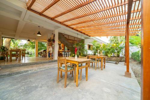 a patio with tables and chairs under a wooden pergola at Casa Chapolin Boutique Guesthouse in Palomino