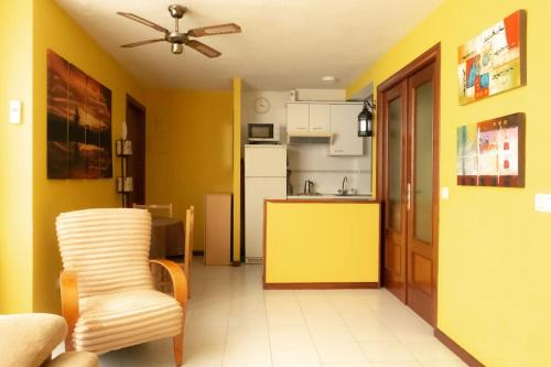ein Wohnzimmer mit einer Küche mit gelber Wand in der Unterkunft Cómodo apartamento en el centro - Gran Vía in Madrid
