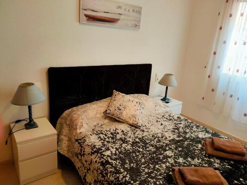 a bedroom with a bed with a black headboard and two lamps at Casas Holiday - Playa del Cura in Torrevieja