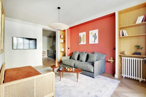 a living room with a couch and a red wall at Le Confidentiel - Montmartre in Paris