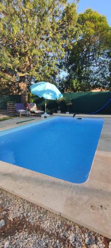 een blauw zwembad met een blauwe parasol bij Appartement proche de la mer in La Garde