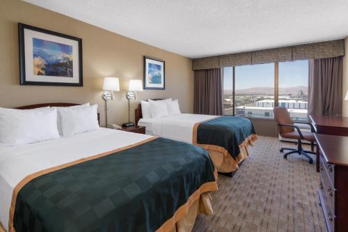 a hotel room with two beds and a balcony at Ramada by Wyndham Reno Hotel & Casino in Reno