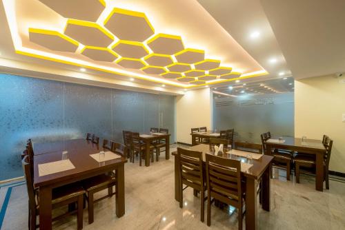 Zenith Hotels Hebbal Bangalore في بانغالور: غرفة طعام بها طاولات وكراسي وسقف