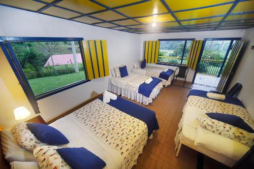 Zimmer mit 3 Betten in einem Zimmer mit Fenstern in der Unterkunft El Rancho de Salento in Salento