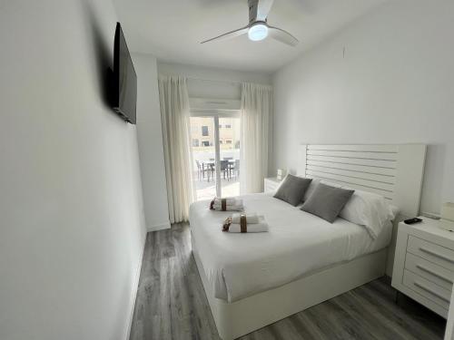 a white bedroom with a white bed and a window at PUSHE Playa Granada Beach & Golf 12 in Motril