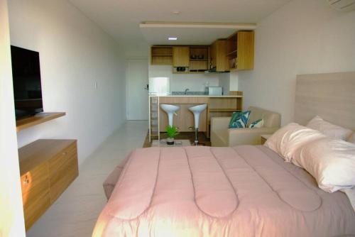 a bedroom with a large pink bed and a kitchen at Hermoso Monoambiente ZV210, Edif Zetta Village Airport in Colonia Mariano Roque Alonso