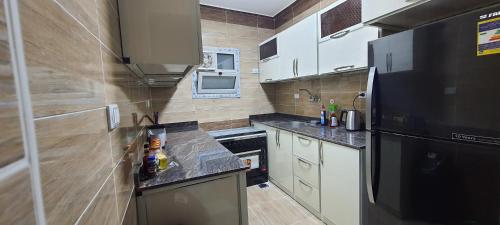 eine kleine Küche mit einem schwarzen Kühlschrank und Schränken in der Unterkunft Meedo Apartments in Kairo