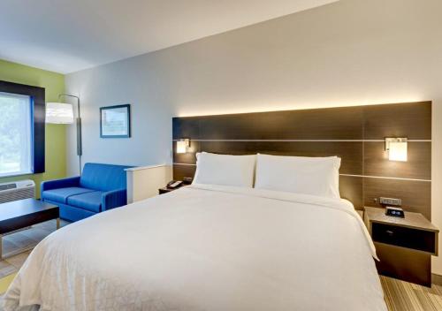 a bedroom with a large bed and a blue chair at Holiday Inn Express & Suites - Winston - Salem SW - Clemmons by IHG in Clemmons