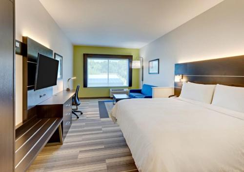 a hotel room with a bed and a flat screen tv at Holiday Inn Express & Suites - Winston - Salem SW - Clemmons by IHG in Clemmons