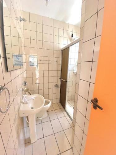 a white bathroom with a sink and a shower at Chalés Sununga Flats a 1 minuto da praia in Ubatuba
