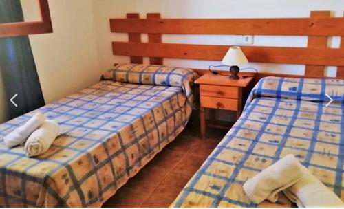 a room with two beds and a table with a lamp at Can Pep Yern 3 in Playa Migjorn