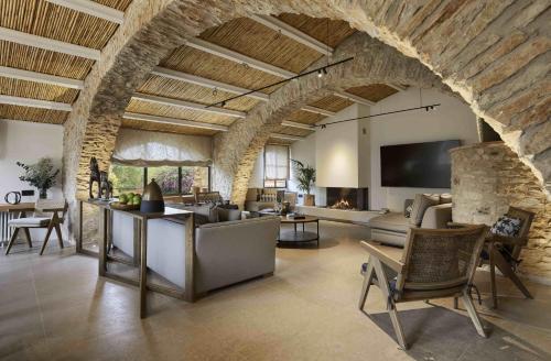 ein Wohnzimmer mit einer Steinmauer, einem Sofa und Stühlen in der Unterkunft Turisme Rural Mas Ametller - Casa Gran in Fontclara