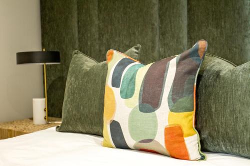a bed with green pillows and a pillow on it at Executive Apartment at Ellipse Waterfall in Midrand