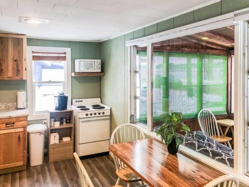 a kitchen with a wooden table and a stove and a window at Cozy pet friendly cabin with dock, firepit, bikes, grill in Newaygo