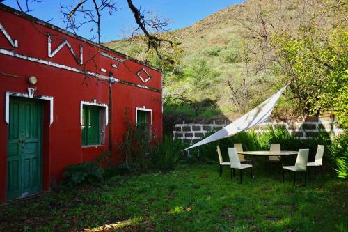 una casa roja con una mesa y sillas en el patio en La Casita, en Vega de San Mateo