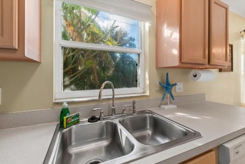 a kitchen with a sink and a window at Heart of the Waves - 3BR & 2BA Beach Retreat - NEW HOT TUB - Outside Patio with Grill & Seating, Steps to Fun! in Melbourne