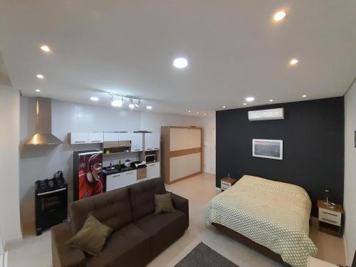 ein Wohnzimmer mit einem Sofa und einer Küche in der Unterkunft JK STUDIO Xavante com Garagem in Pelotas