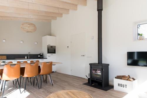 a kitchen and living room with a stove and chairs at Vakantiehuis Eikzicht gelegen aan het bos in Elsloo