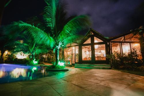 a house with a palm tree in front of a building at Paua Hotel Boutique in Pipa