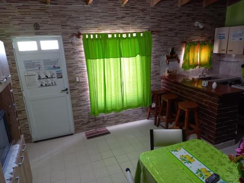 una cucina con tende verdi, un tavolo e un bancone di CRISNANBEL a Las Grutas