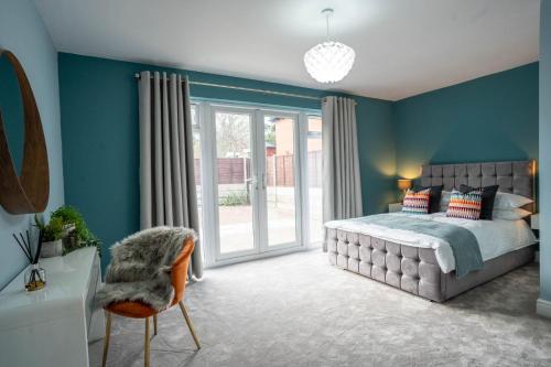 a bedroom with blue walls and a bed and a chair at All Saints House in Worcester