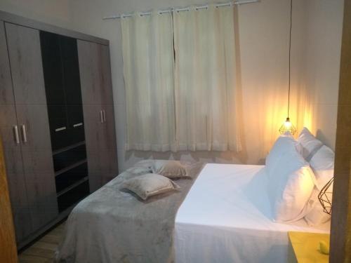a bedroom with a large white bed with a window at Recanto dos Amigos in Santa Teresa