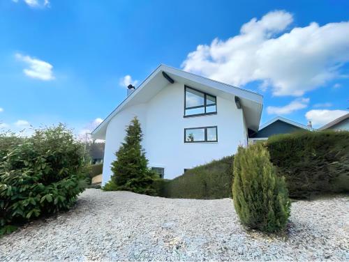 uma casa branca no topo de uma colina com arbustos em Hochwertige Wohnung mit Parkplatz im schönen Schwarzwald em Altensteig