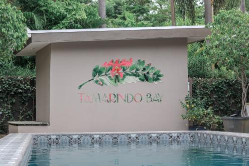 a sign on a wall with a swimming pool at Tamarindo Bay Boutique Hotel, Apartments & Suites in Tamarindo