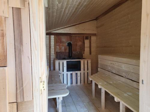 a wooden cabin with benches and a stove in it at Pensiunea ANA Vistisoara in Vistisoara