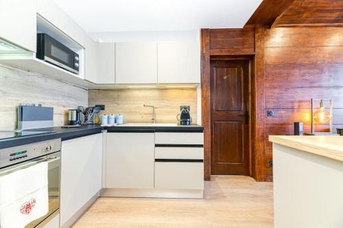 - une cuisine avec des placards blancs et un mur en bois dans l'établissement Penthouse-Chalet in Arc 1950 SKI IN-SKI OUT, à Arc 1950